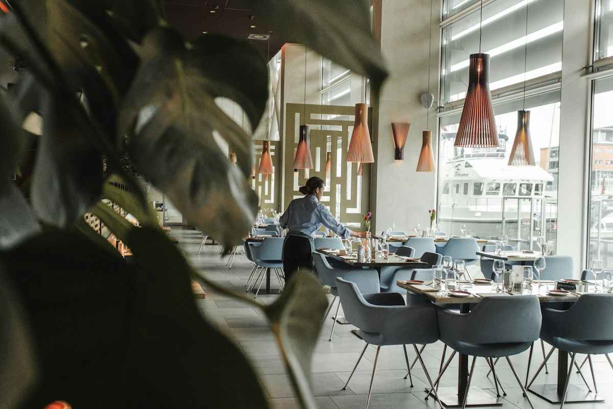 A restaurant server setting tables in a bright hotel dining room, the kind of role where the first 30 days decide whether a new hire stays
