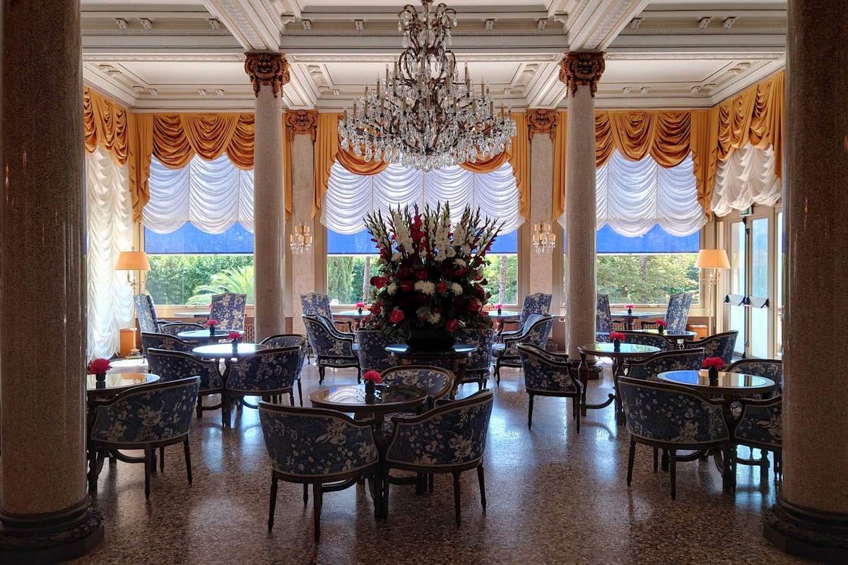 Grand Belle Epoque hotel lounge with chandelier, draped windows and upholstered seating — the operating business that sits behind every hotel valuation
